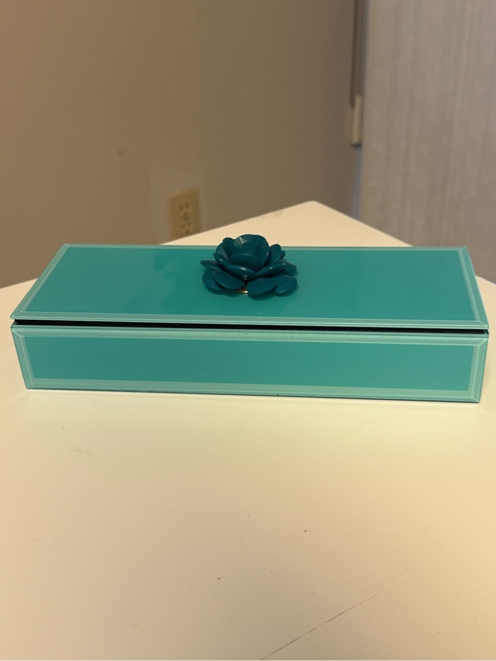 Teal glass jewelry box featuring a built in mirror, ring rolls, ample storage